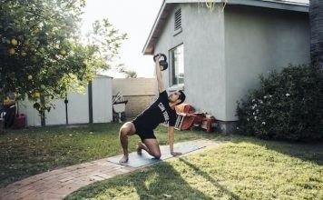 Hombre realizando un turkish get-up en el jardin