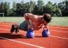 chico realizando entrenamiento con kettlebell en pista de atletismo
