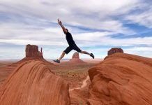 hombre saltando entre rocas en una llanura con los brazos estirados