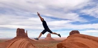 hombre saltando entre rocas en una llanura con los brazos estirados