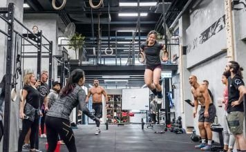 chica realizando ring muscle up en el box con atletas apoyando