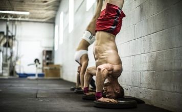 Hombre y mujer realizando un HSPU en CrossFit
