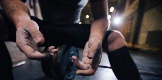 chico sentando sobre discos enseñando sus manos en crossfit